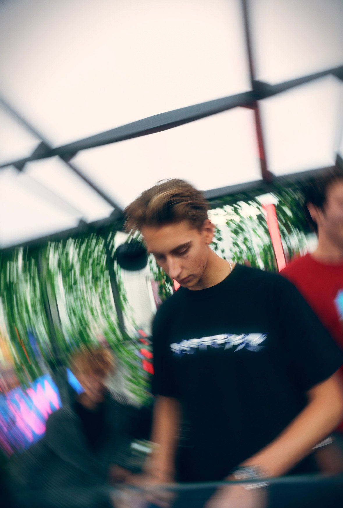 Motion blur shot of a FØR U DJ in a black T-shirt focused on the mixer at an outdoor booth