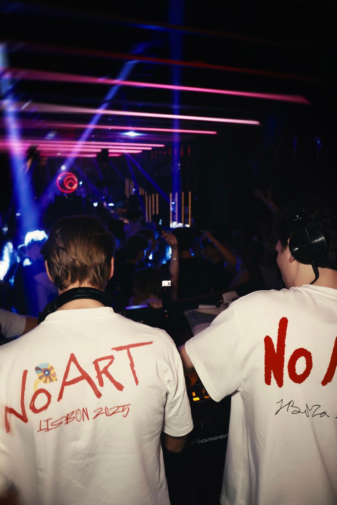FØR U duo seen from behind in matching No Art Lisbon 2025 T-shirts, pink lasers over the crowd